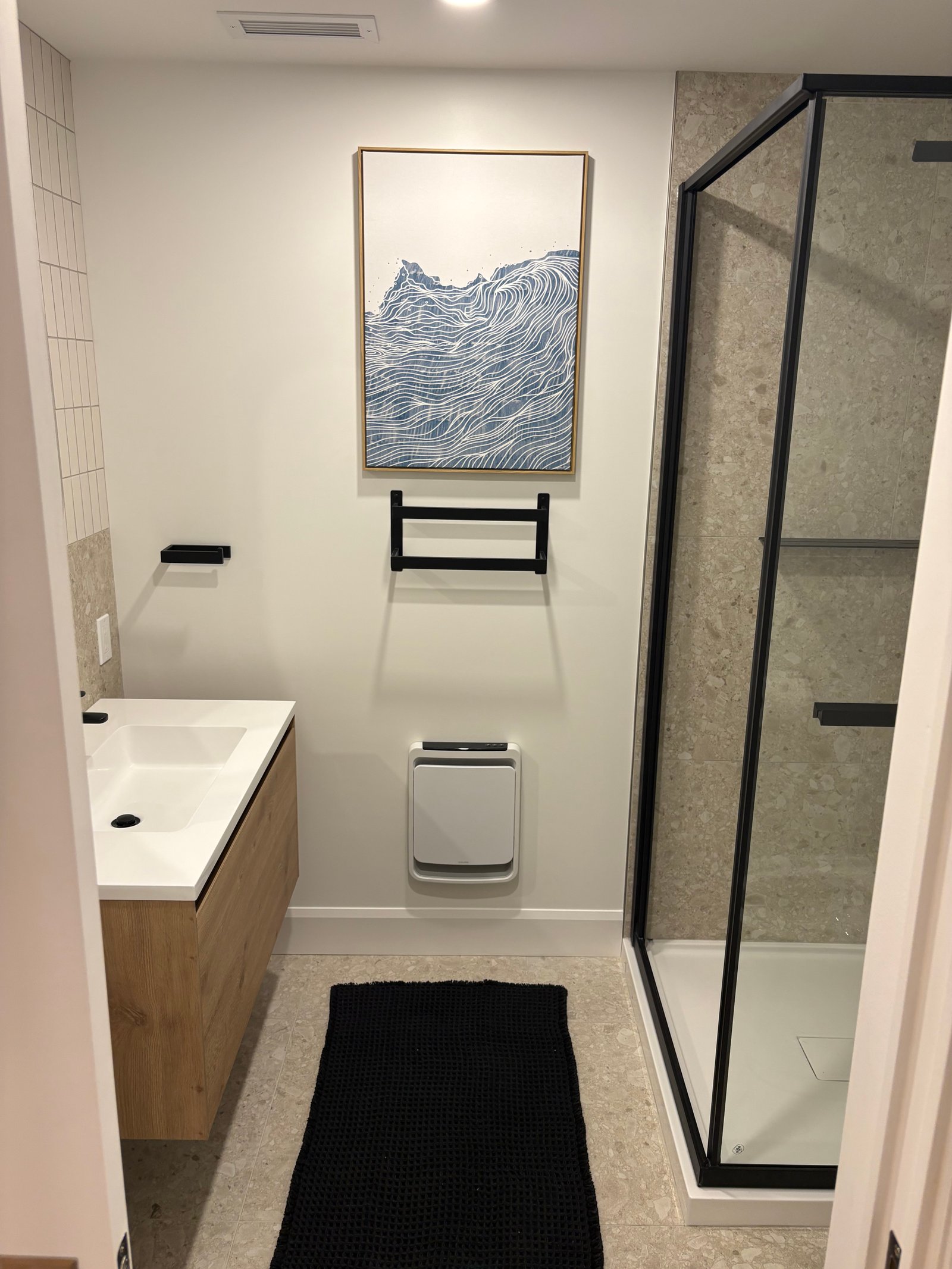 Salle de bain Lévis — Douche vitrée noire, vanité bois et carrelage pierre